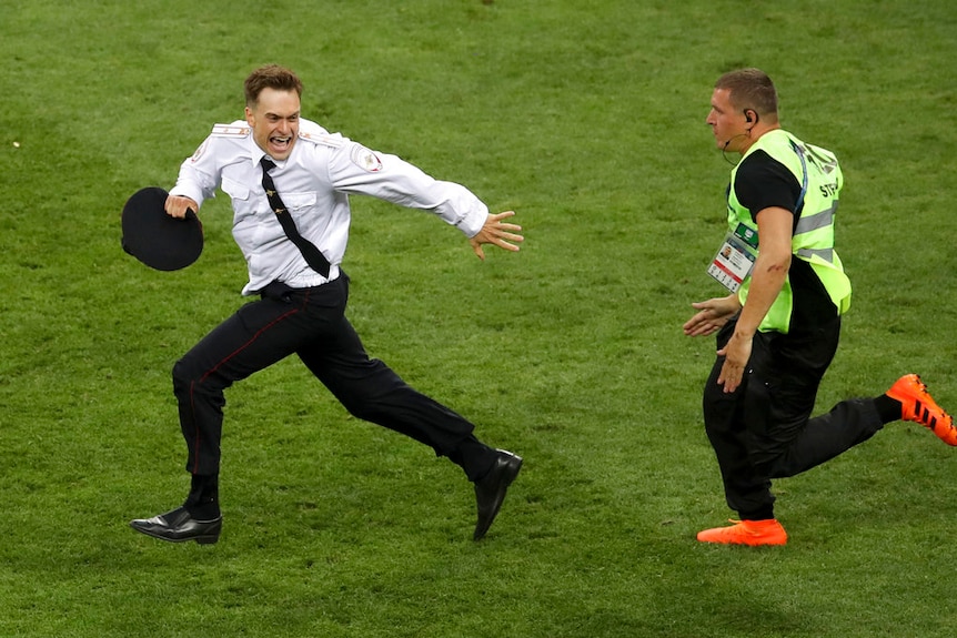 Pyotr Verzilov invaded the pitch, runs away as a steward tries to stop him.