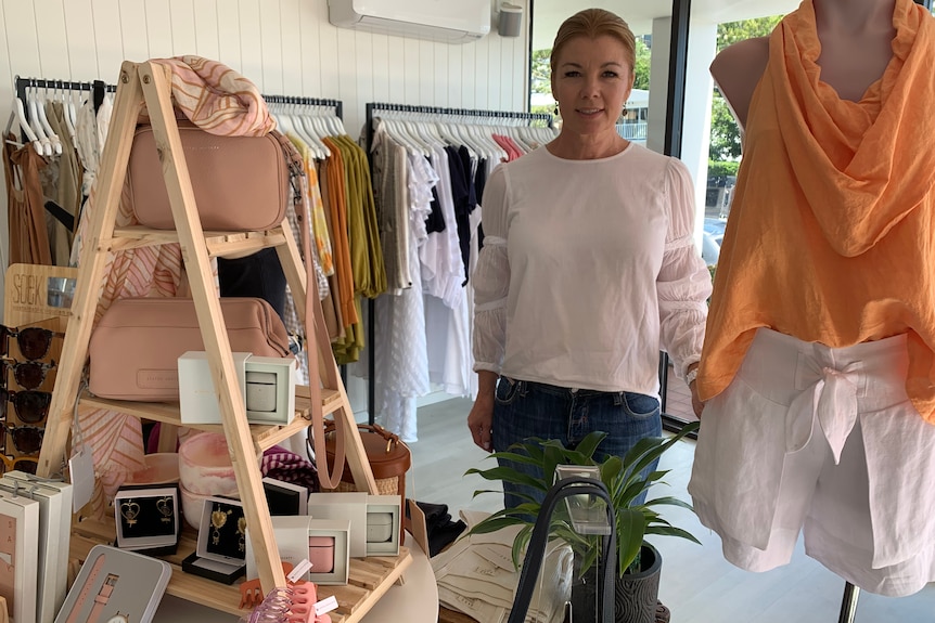 Currumbin clothes shop owner Jodie Love standing in her shop surrounded by clothes and bags