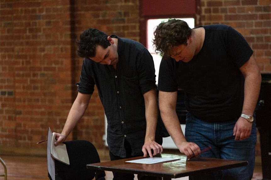 Two men looking at a script in a rehearsal for a play