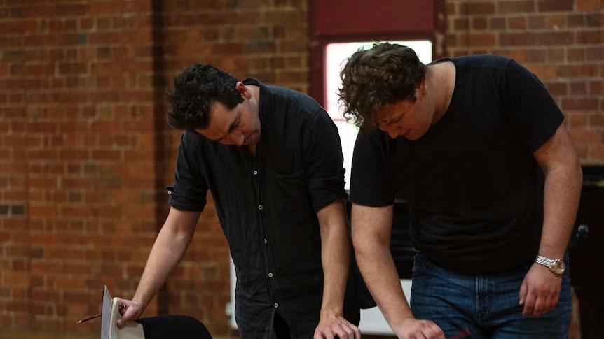 Two men looking at a script in a rehearsal for a play