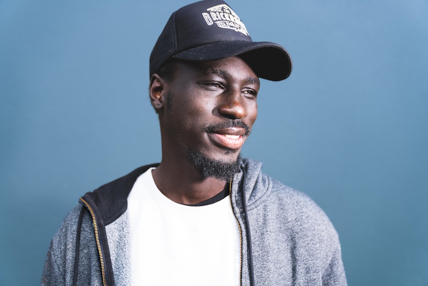 A man wearing a baseball cap looks to the side