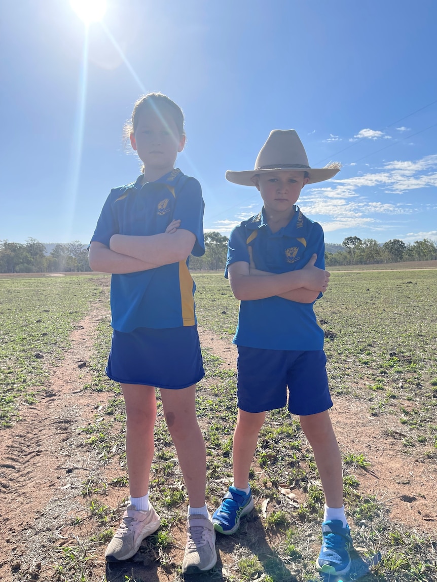 Two young kids standing in a horse paddock.