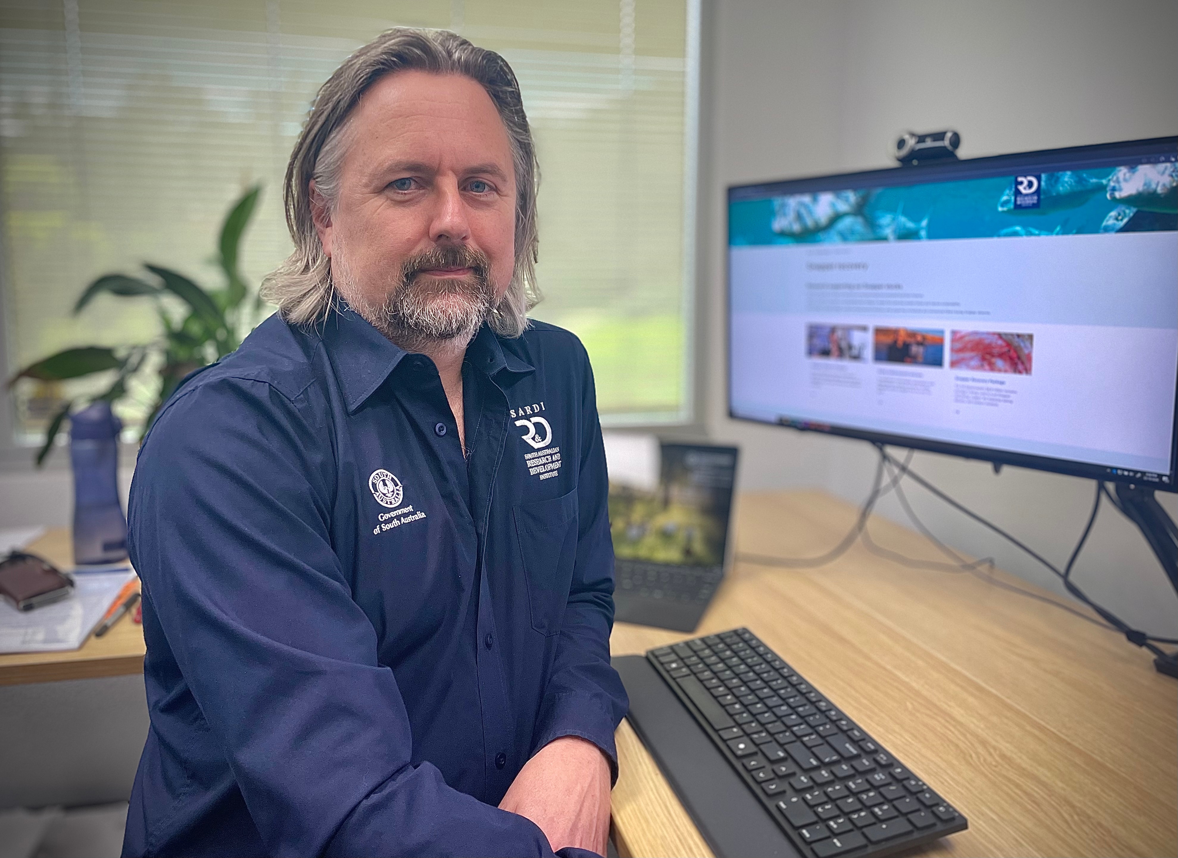 The male SARDI executive director sits at a computer looking toward the camera