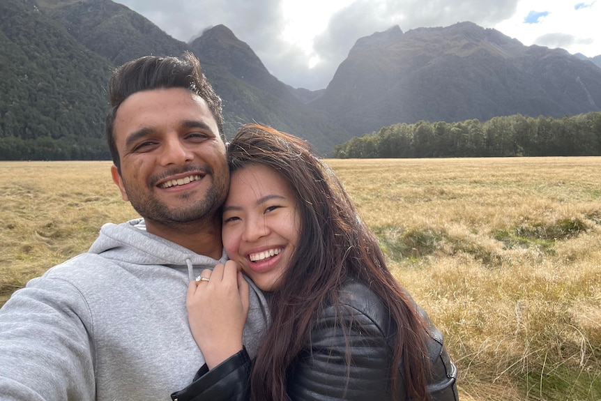 A man and a woman smiling in the middle of a green valley