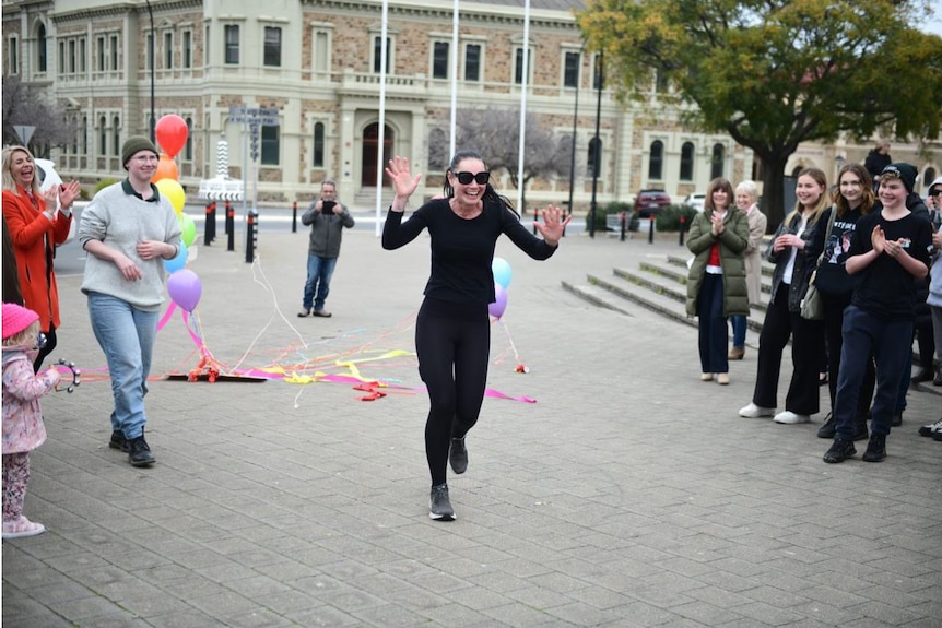 Lee-Anne Lupton smiling as runs past people clapping and cheering