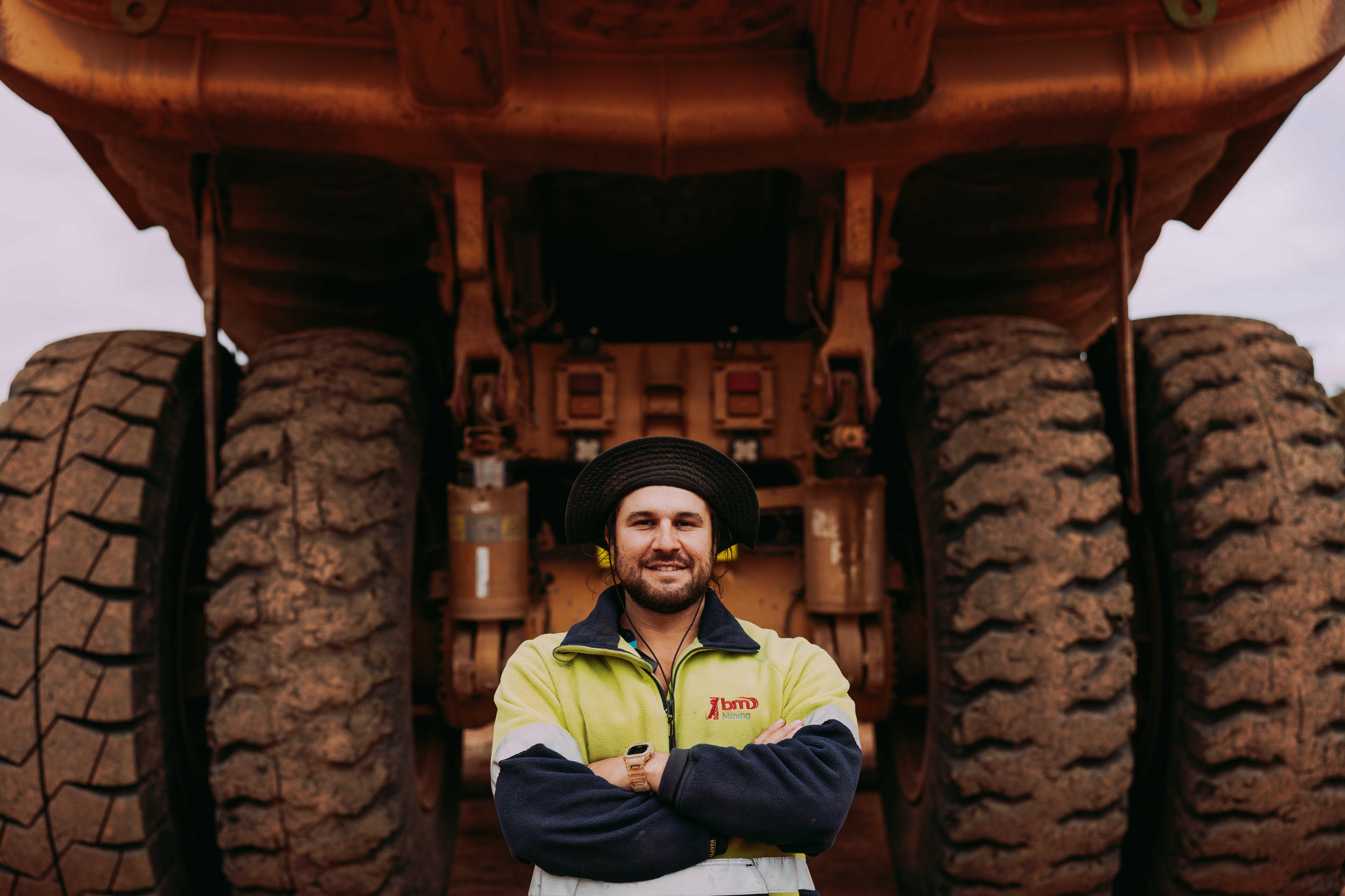 A man standing in front of tyres of a massive mining truck. 