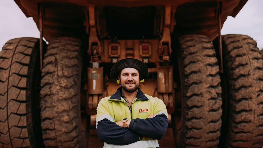 A man standing in front of tyres of a massive mining truck. 