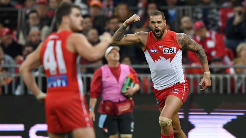 Lance Franklin pumps his fist while Tom Papley, blurred in the foreground, joins in.