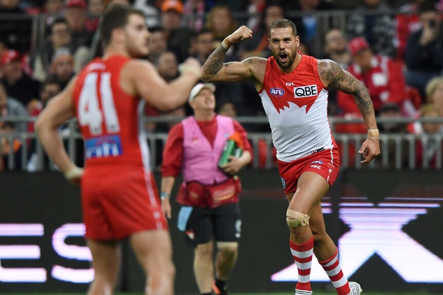 Lance Franklin pumps his fist while Tom Papley, blurred in the foreground, joins in.