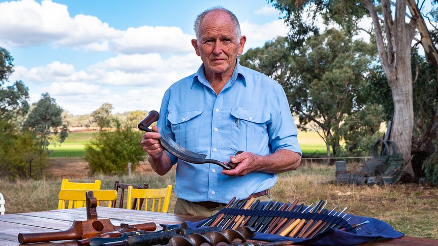 A man posing with traditional woodworking tools.