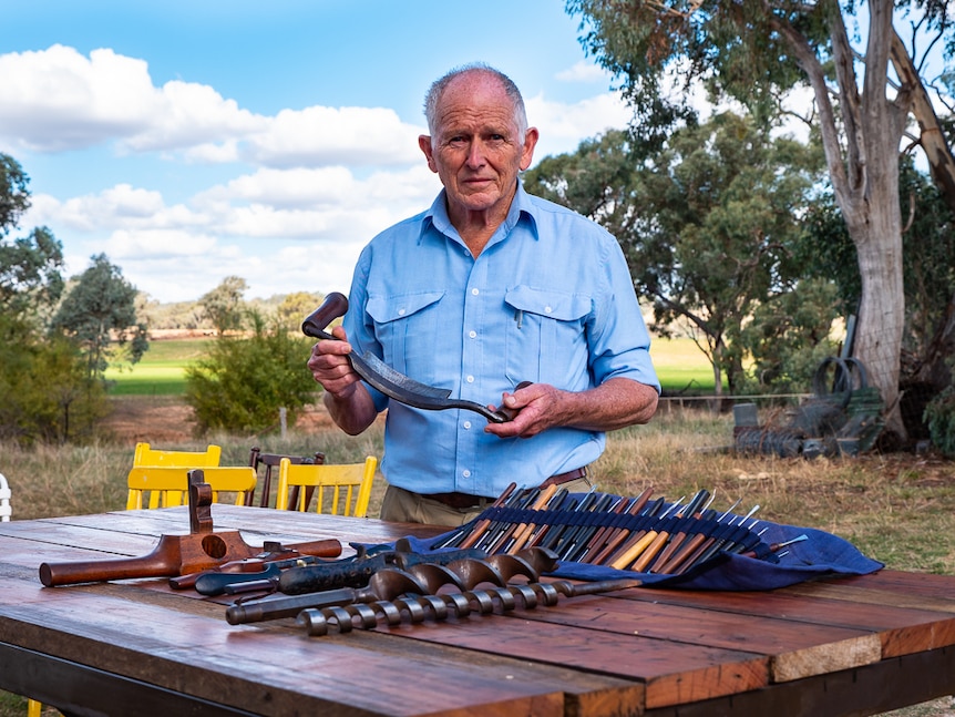 A man posing with traditional woodworking tools.