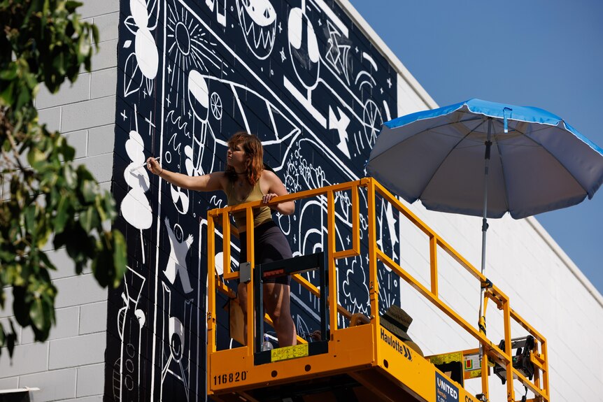  woman painting a large black and white mural