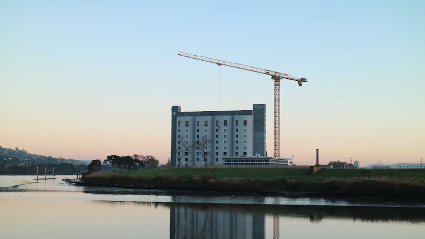a large crane hangs over a set of grain silos