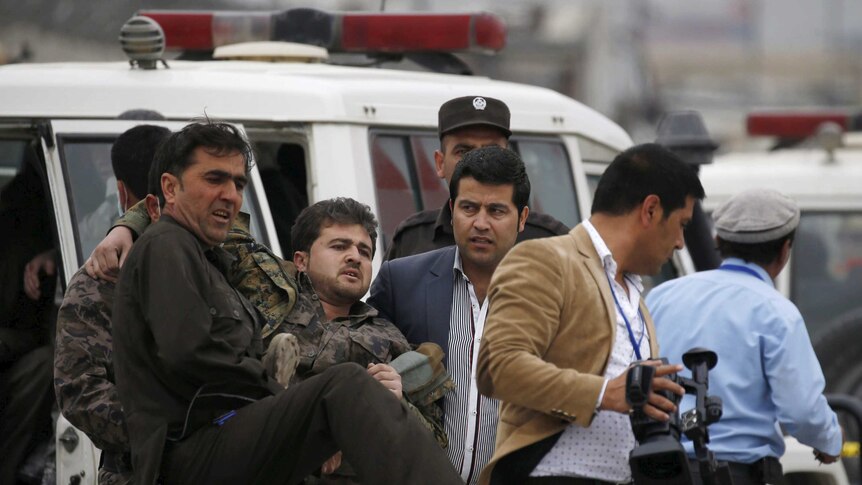 Men carrying an injured security personnel.