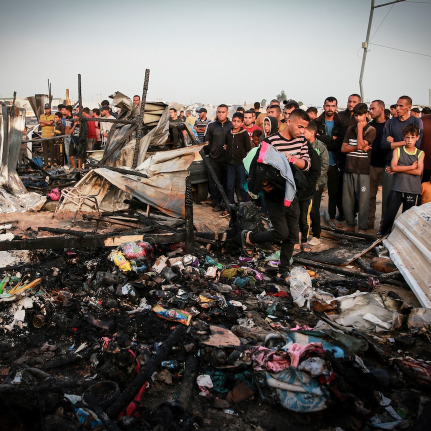 Palestinians look at burnt buildings and debris after an Israeli strike.