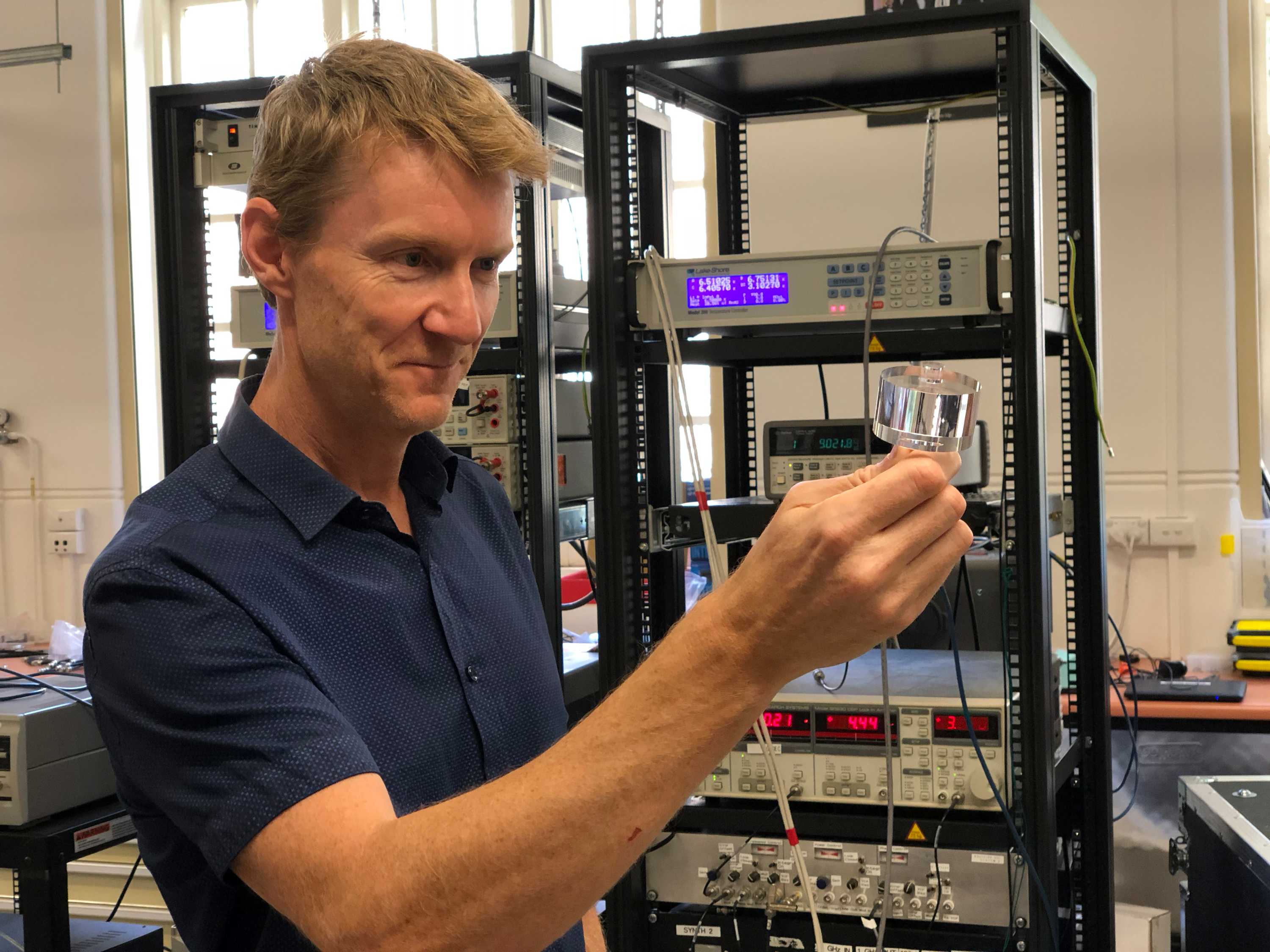 Associate Professor Martin O'Connor smiles as he holds the sapphire clock crystal.