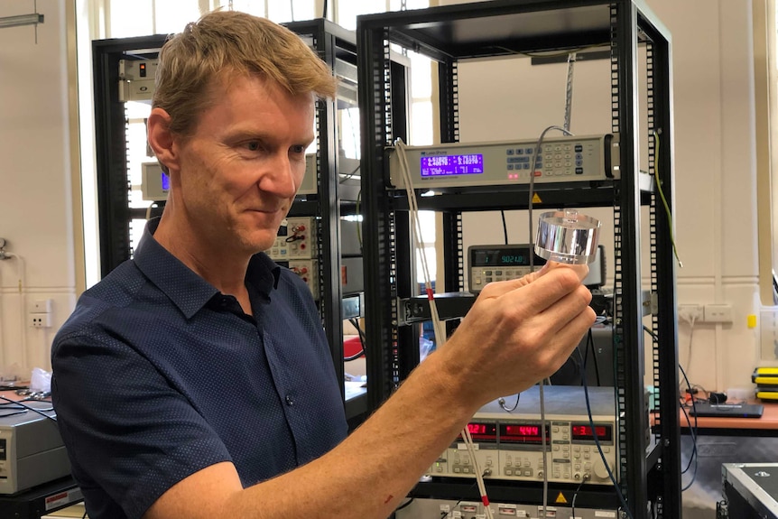 Associate Professor Martin O'Connor smiles as he holds the sapphire clock crystal.