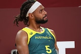Australian basketballer patty mills sits on a chair with a towel looking like he is about to cry
