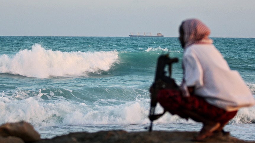An armed Somali pirate keeps watch off the coast of Hobyo