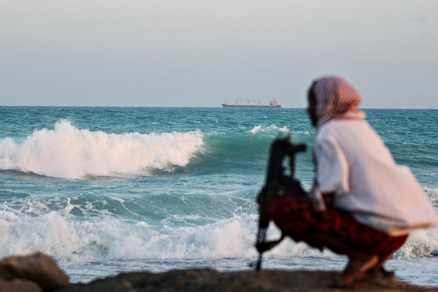 An armed Somali pirate keeps watch off the coast of Hobyo