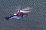 A helicopter hovering over water. 