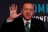 Turkish President Tayyip Erdogan holds up his hand during a speech.