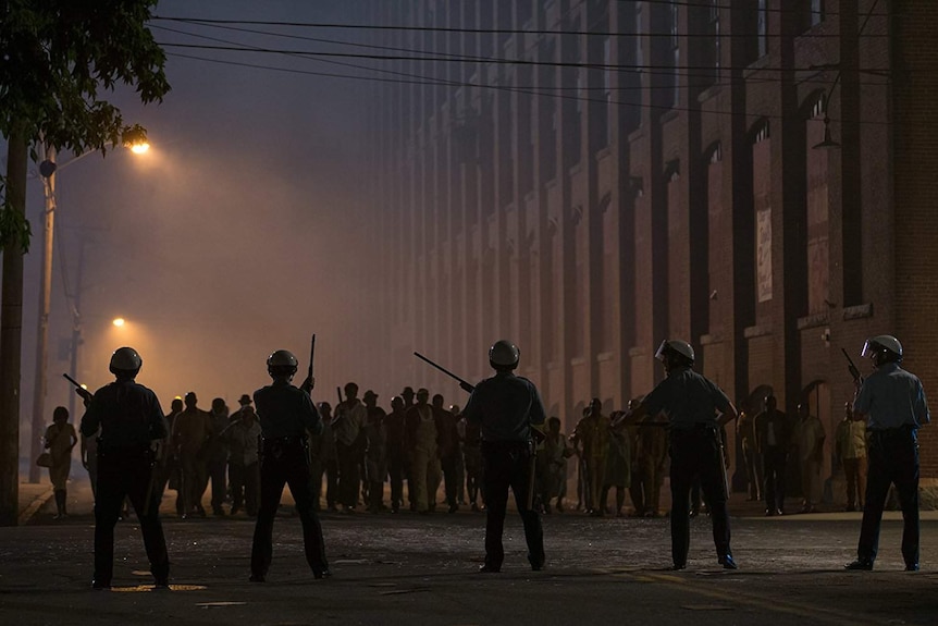 Still image from 2017 film Detroit of rioters and riot police facing off in the street at night time.
