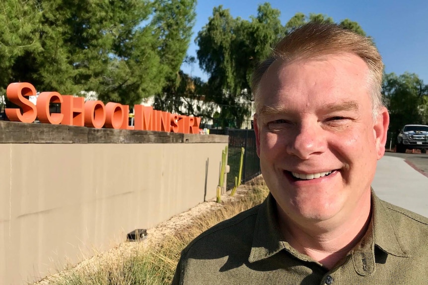 Pastor Shawn Thornton in front of the school ministry sign