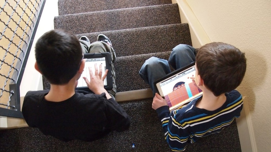 Two children use an iPad