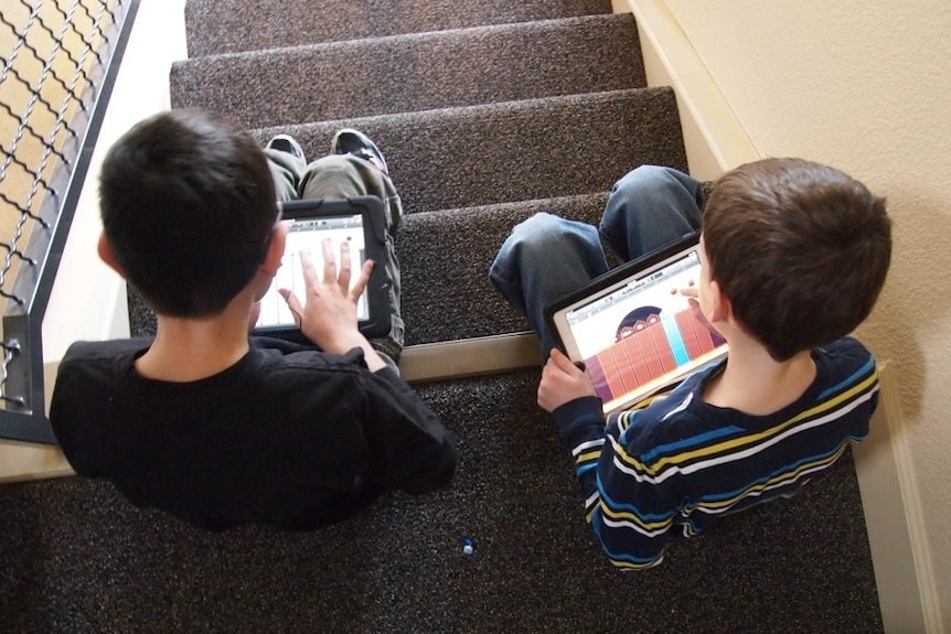 Two children use an iPad