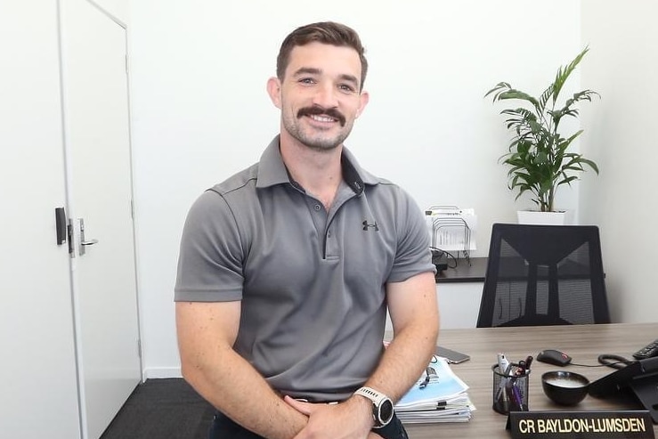 A young man sitting on his desk.