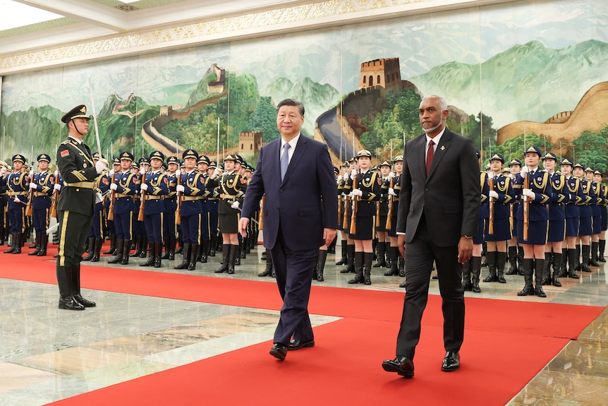 The Maldivian and Chinese Presidents walk down a red carpet together in front of a formation of Chinese soldiers.