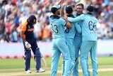 Chris Woakes is hugged by three teammates as Rohit Sharma walks off in the background.