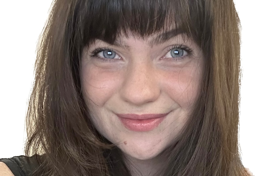 A young woman with brown hair with fringe and blue eyes smiles 