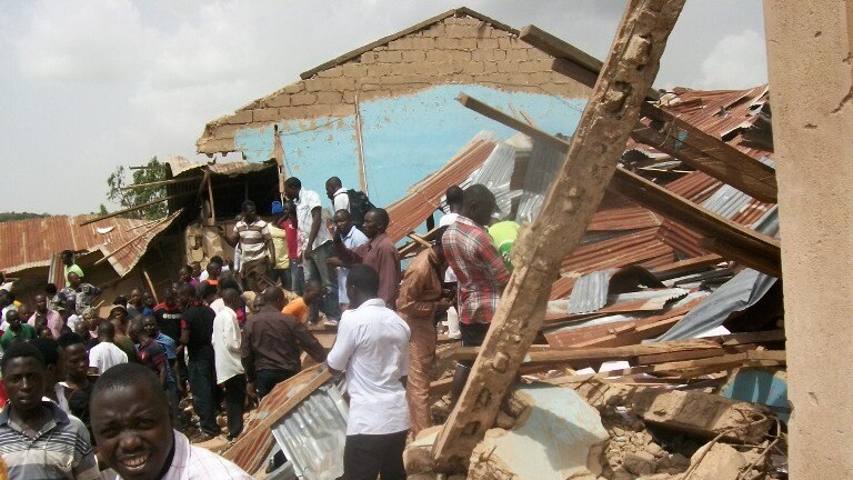 People gather outside the ruins of a church targeted by a suicide bombing in a church in Jos.