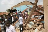 People gather outside the ruins of the church in Jos where a suicide bomber killed two worshippers.