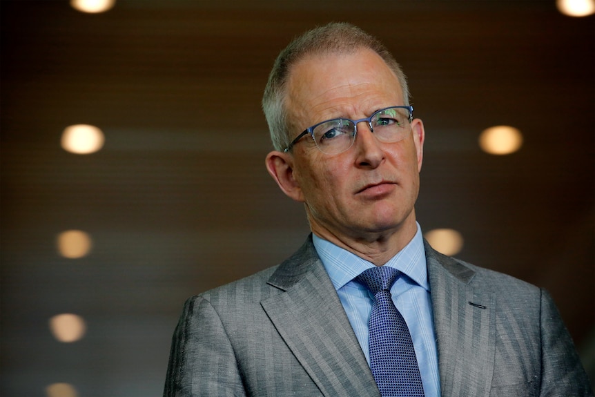 Communications Minister Paul Fletcher wearing a suit looking at media at press conference in June 2021. 