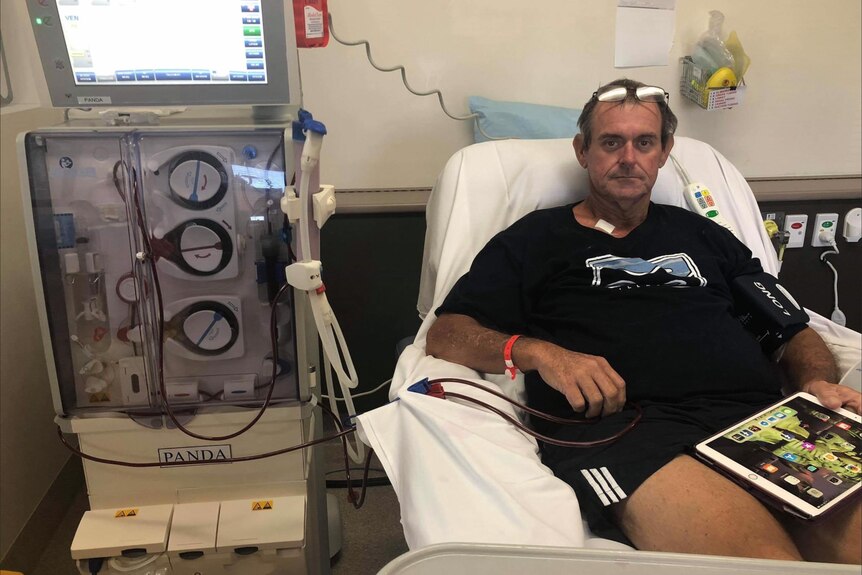A man sits in hospital bed hooked up to a dialysis machine 