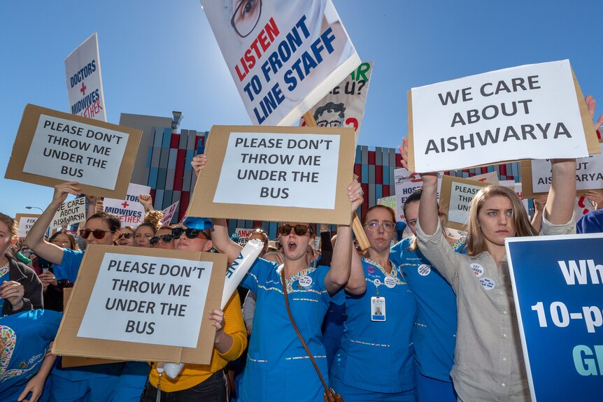 A group of nurses holding placards high above their heads