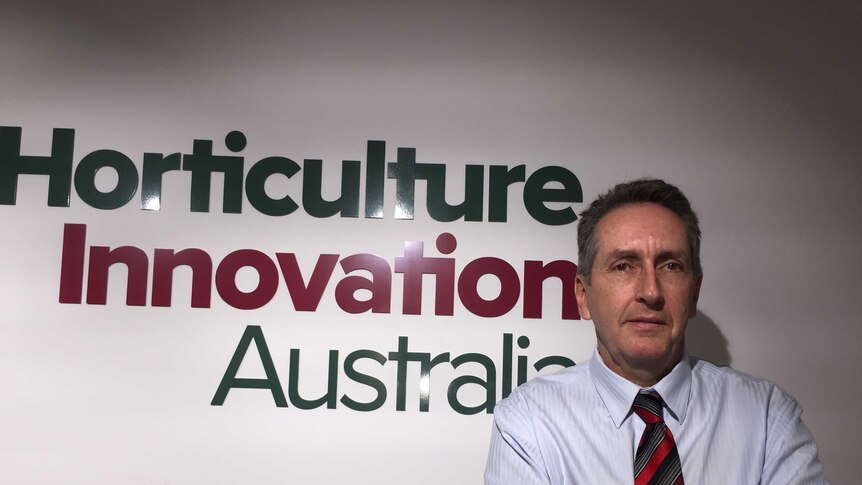 John Lloyd stands arms folded in front of Horticulture Innovation Australia sign at Headquarters in Sydney