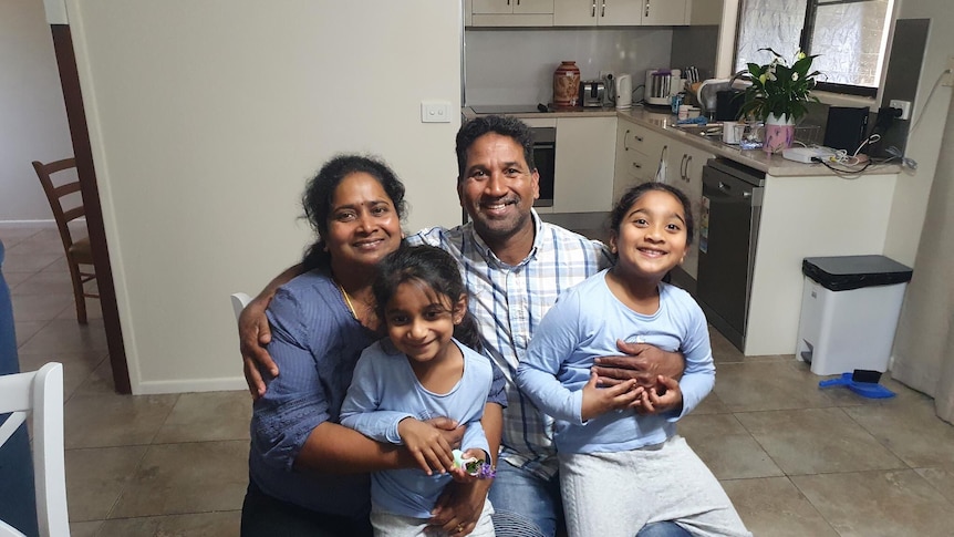 Tamil asylum seeker family the Nadesalingams smile and hug in their home.