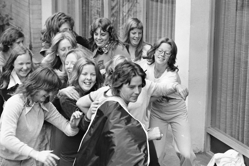 Black and white photo of women chasing John Paul Young in the street.