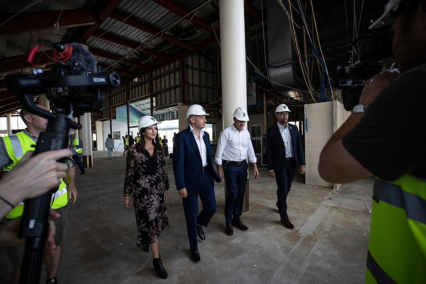 Four people wearing hard hats walk through a construction site.