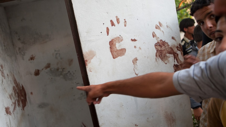 Syrians show blood stains on the wall of a house in the Syrian village of Treimsa.