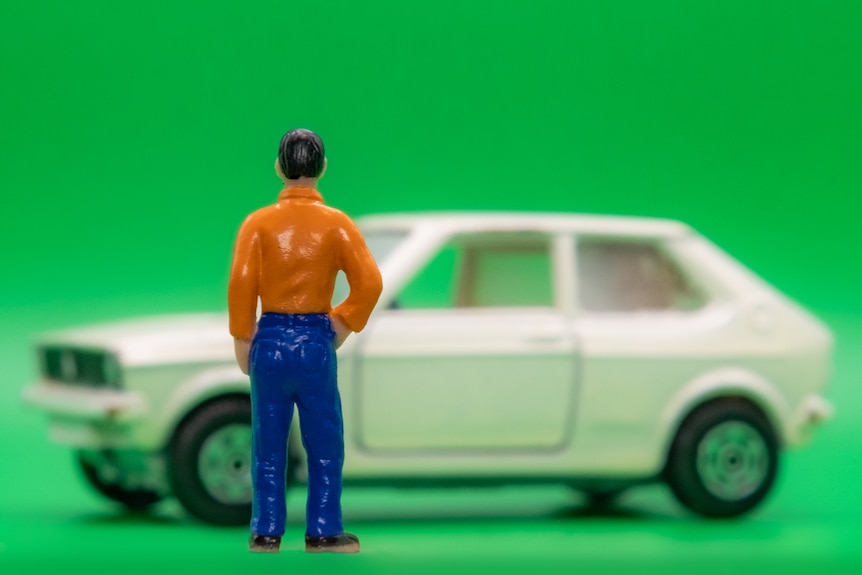 A photo of a miniature man next to a VW.