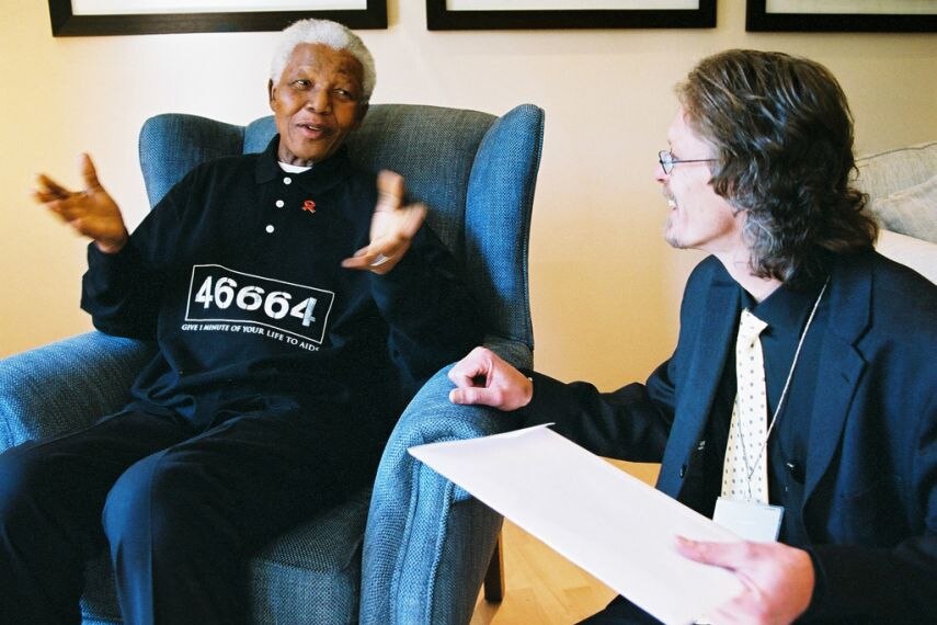 Nelson Mandela and Verne Harris sit on lounge chairs and talk.