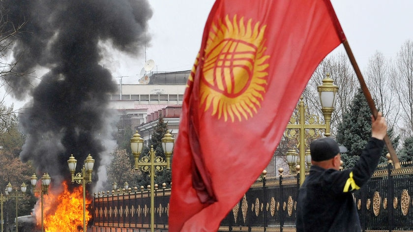 A Kyrgyz opposition supporter waves the national flag during violent protests against the government