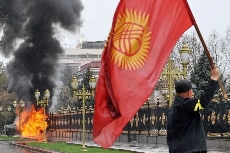 A Kyrgyz opposition supporter waves the national flag during violent protests against the government