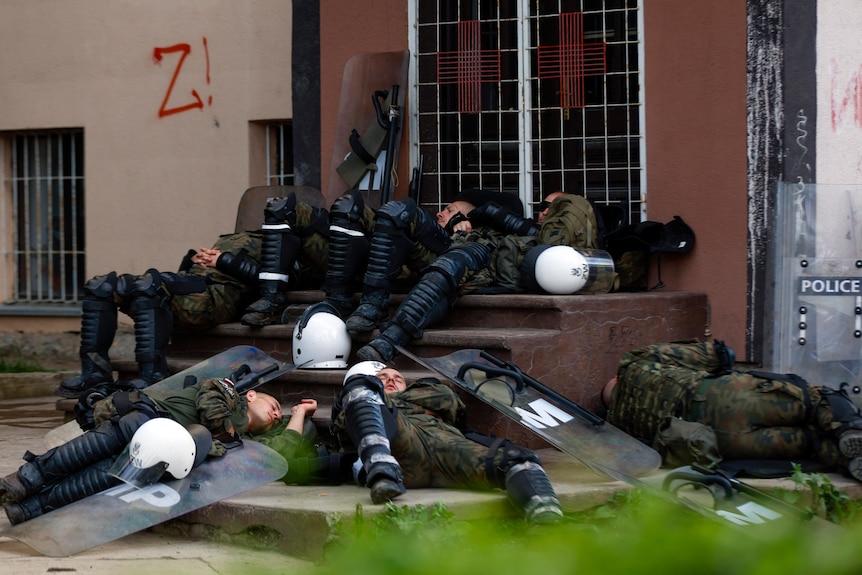 Polish soldiers lie down on steps in front of a municipal building.