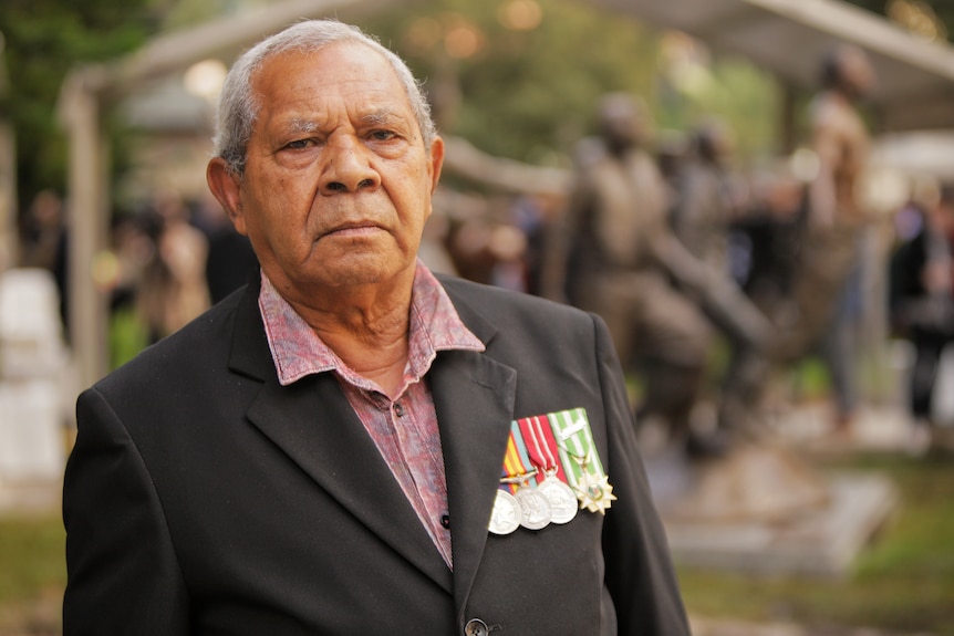 Indigenous man wearing a suit jacket with military medals pinned.